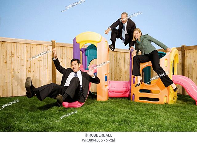 Two businessmen and a businesswoman playing with jungle gym