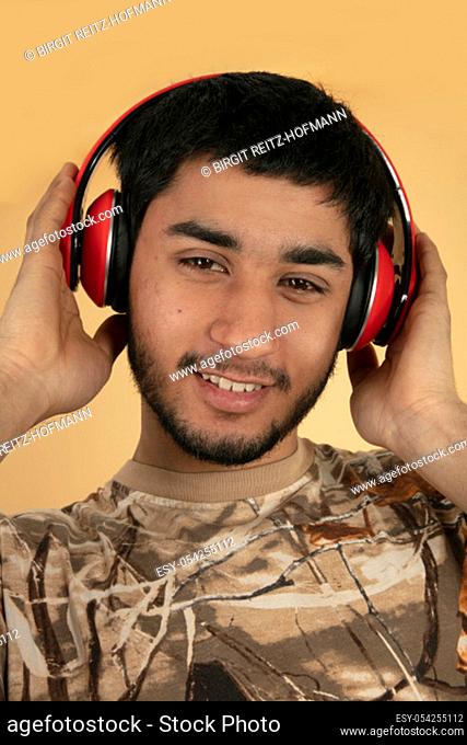 Young Man with Headphones listen to Music on beige Background