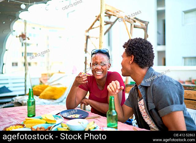Happy young couple eating lunch at patio table