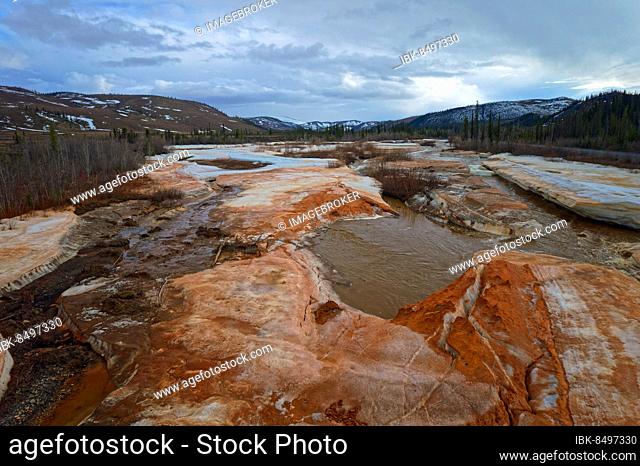 Drone shot, ice break-up, ice deposits, iron minerals, sulphurous, rust-coloured water, Engineer Creek, Dempster Highway, Yukon, Canada, North America