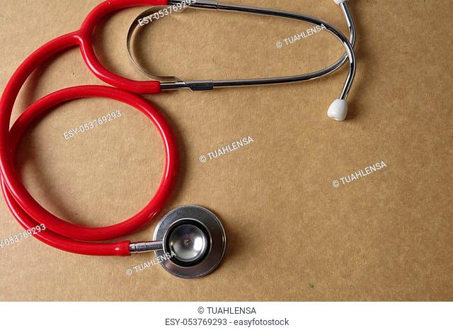 Red stethoscope on wooden background. Medical and health care concept