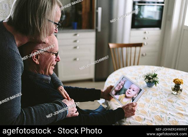Smiling couple having video chat with baby grandson on tablet