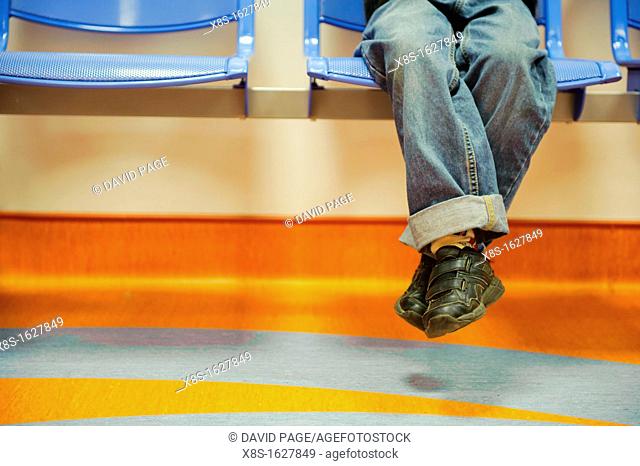 Stock photo of a boys legs swinging from a chair