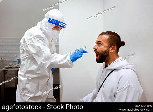 Cologne, North Rhine-Westphalia, Germany - Covid rapid test at the Medicare test center, throat swab on cotton swab (posed scene)