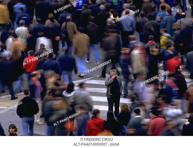 Crowd walking by man standing in opposite direction, blurred motion