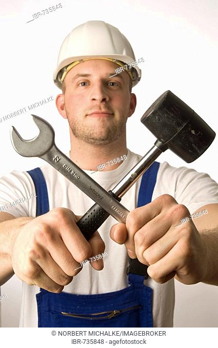 Construction worker holding tools, open-end wrench and hammer