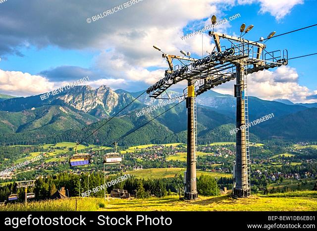 Zakopane, Lesser Poland / Poland - 2019/06/29: Panoramic view of the Tatra Mountains over the Zakopane resort with cable chairlift to the Butorowy Wierch peak