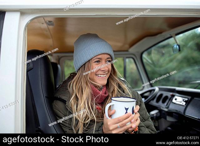 Feliz joven bebiendo café en la puerta de la autocaravana