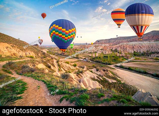 Flying on the balloons early morning in Cappadocia. Colorful sunrise in Red Rose valley, Goreme village location, Turkey, Asia