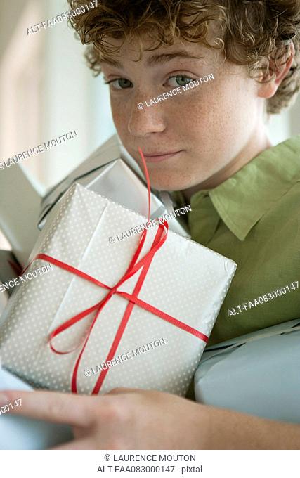 Preteen boy holding pile of presents