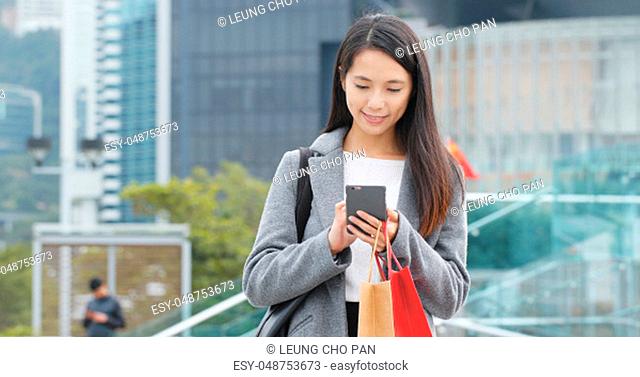 Woman holding shopping bag and look at mobile phone