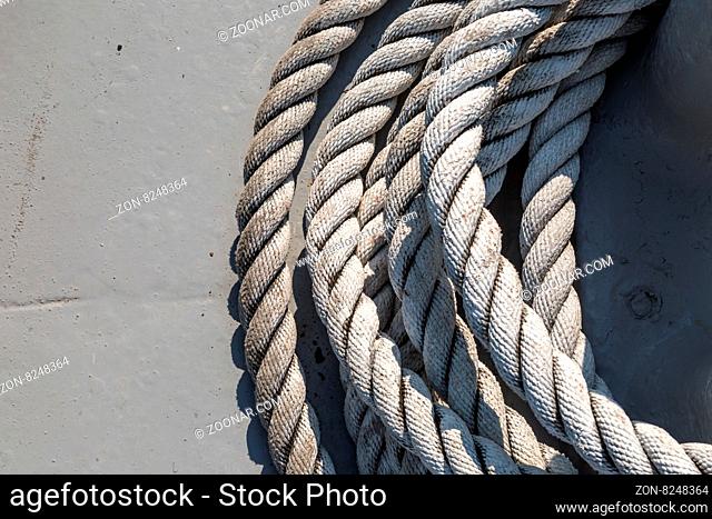 Close up detailed top view of grey nautical rope at an open deck of a ship