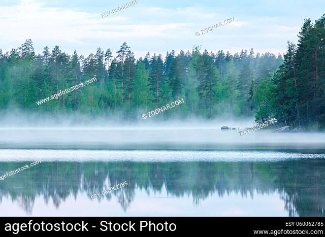 Foggy calm lake and forest at summer night Finland
