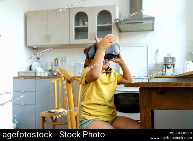 Girl with virtual reality simulator gesturing in kitchen