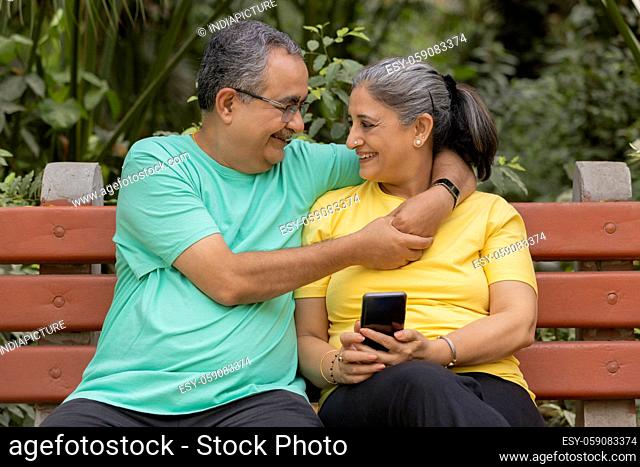 A SENIOR ADULT COUPLE LOVINGLY LOOKING AT EACH OTHER WHILE IN PARK