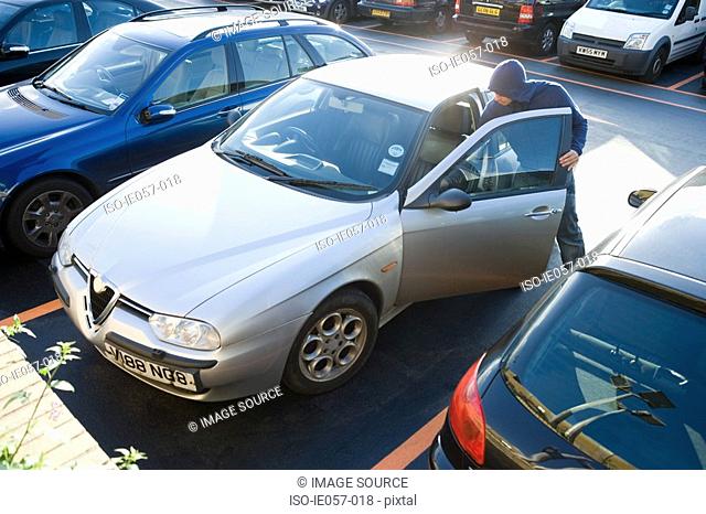 A thief breaking into a car