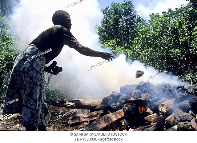 Woman throwing stones on a smoky fire, Sulphur Bay Village, Ipekel Ipeukel, Tanna Island, Vanuatu