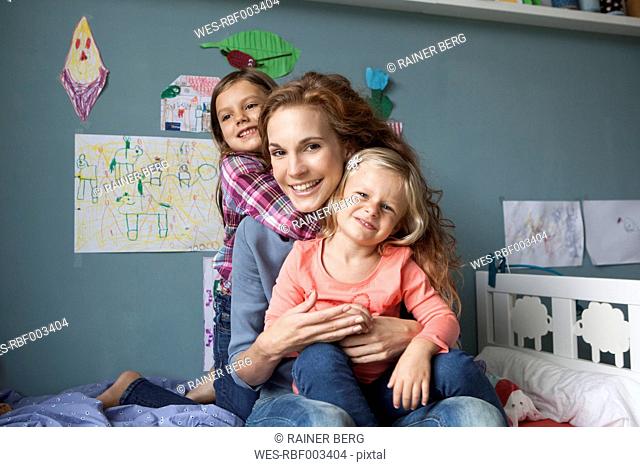 Portrait of woman with her little daughters in children's room