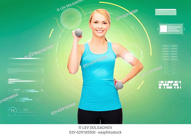 sport, fitness, exercising, technology and people concept - happy young sporty woman with dumbbells flexing biceps over green background