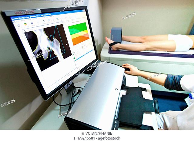 A doctor uses a bone densitometer to measure the optical density of the neck of the femur of female patient to diagnose osteoporosis