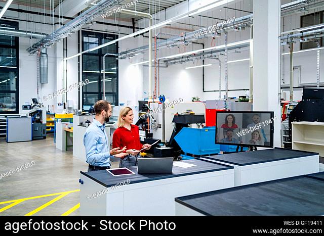 Happy business colleagues doing video call on computer screen at factory