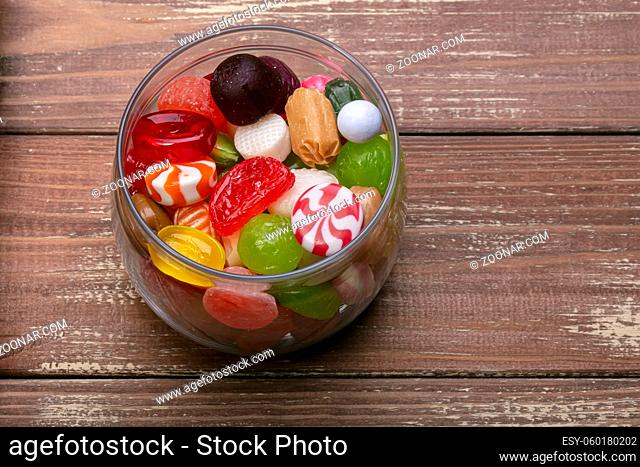 Candies in a jar on a wooden background. Multi-colored caramel. Sweets