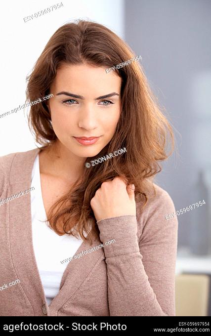 Attractive daydreaming woman standing at wall at home