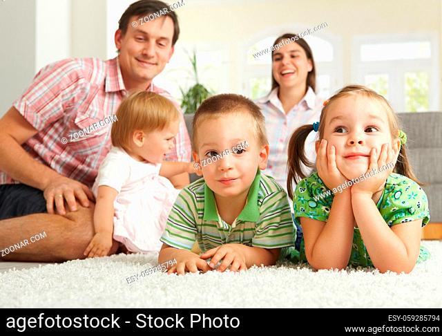 Happy family with 3 children sitting on floor of living room at home