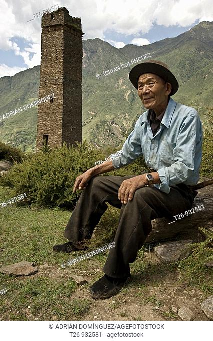 A man taking a rest in the mountain with an old tower behind in Sichuan Province