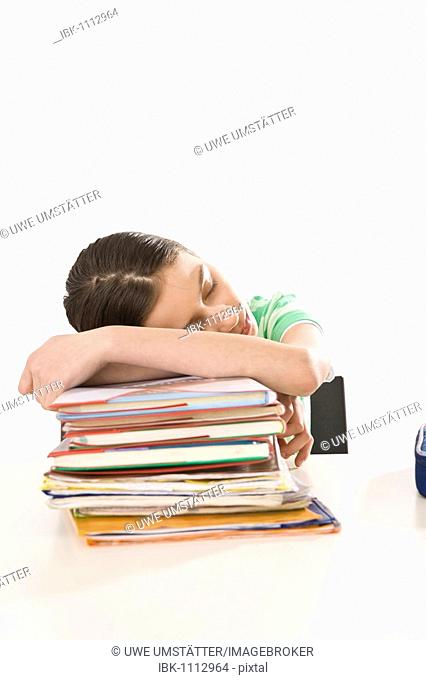 Girl sleeping on a pile of exercise books and school books