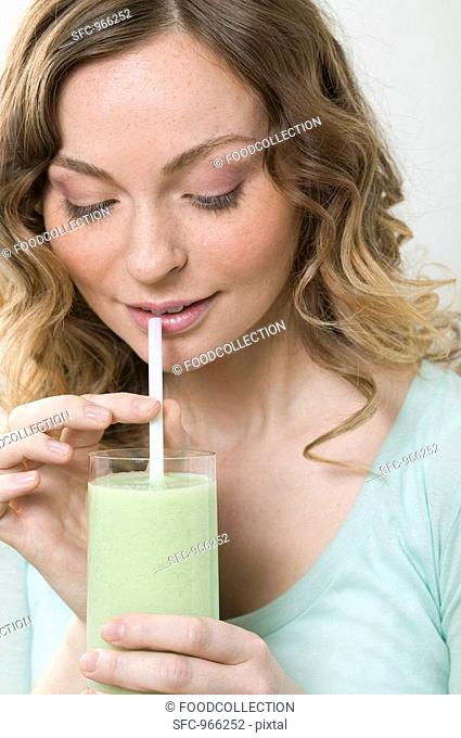 Woman drinking cucumber shake through a straw