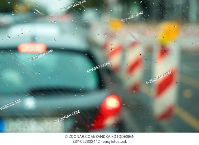 A car is driving on the road in the rain