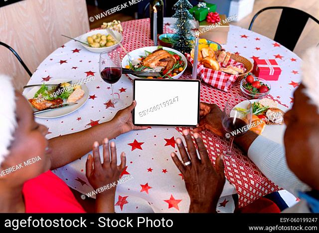 Back view of african american senior couple using tablet with copy space at christmas time