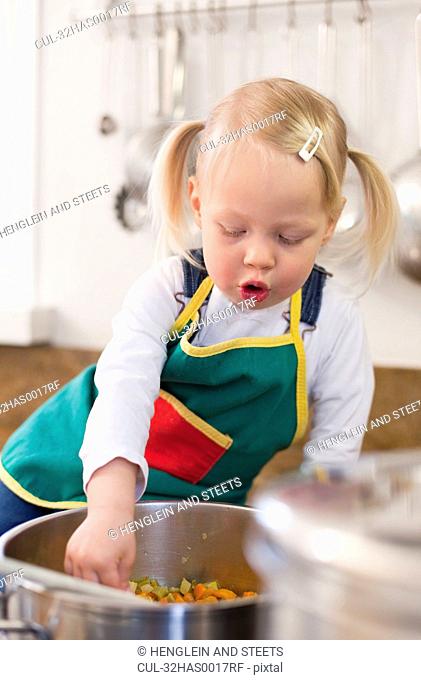 Toddler girl cooking in kitchen