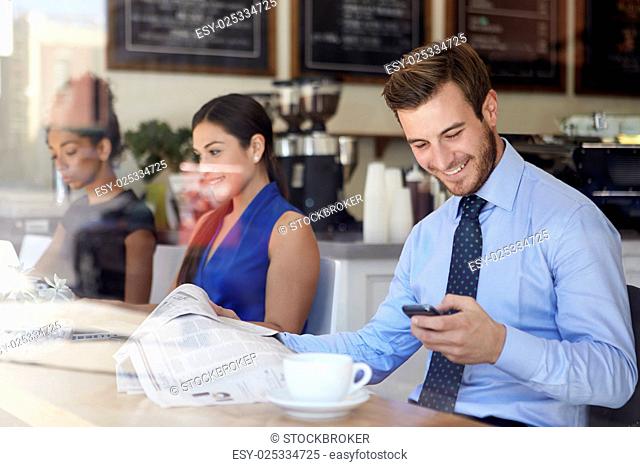 Businessman With Mobile Phone And Newspaper In Coffee Shop