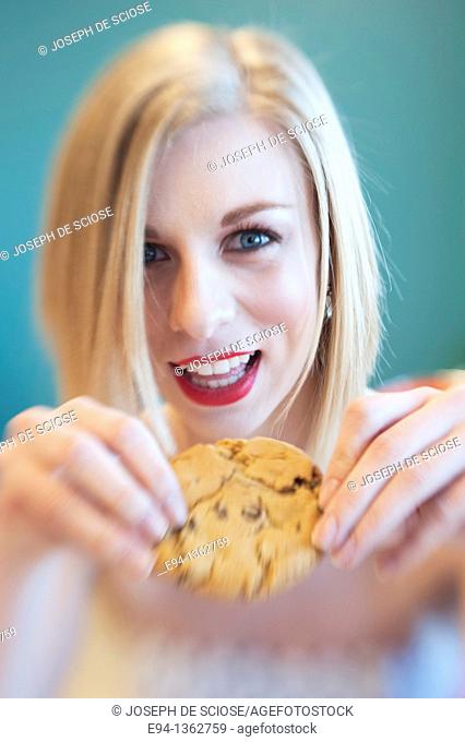 19 year old blond woman holding a chocolate cookie
