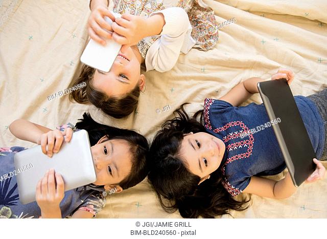 Girls laying on blanket using cell phone and digital tablets