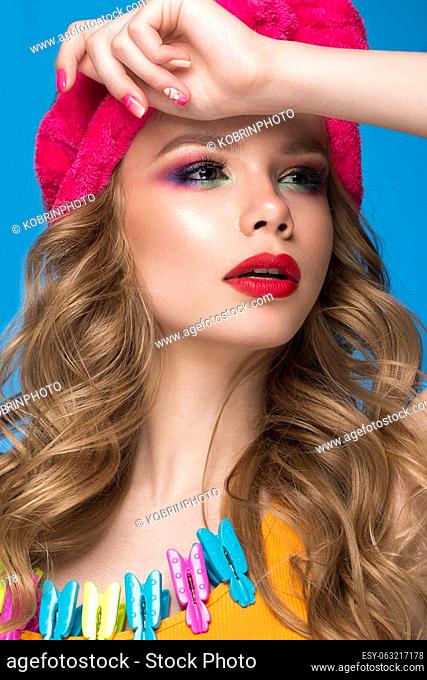 Bright cheerful girl in a home hat, colorful make-up, curls and pink manicure. Beauty face. Photo taken in the studio