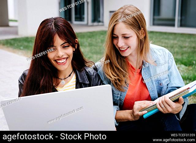 Smiling young multi-ethnic female students using laptop at campus