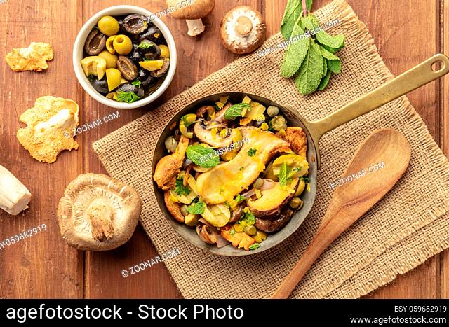An overhead photo of a rustic mushrooms and olives saute with mint and porcini