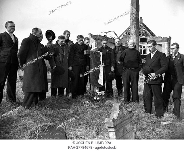 Almost all tombs on Helgoland are destroyed. Therefore these men are laying down flowers at the simple wooden cross on 1st March 1952
