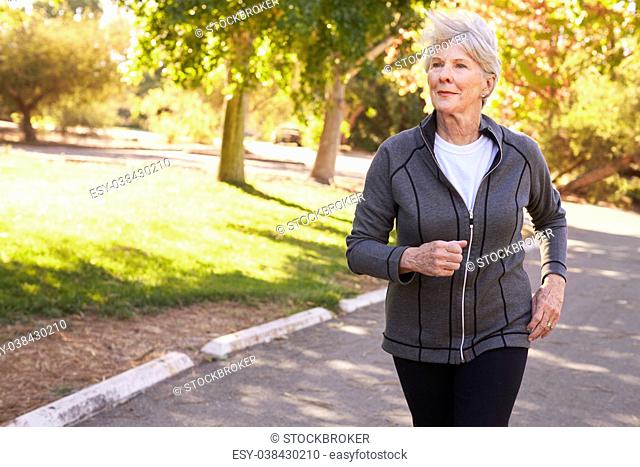 Front View Of Senior Woman Jogging Through Park