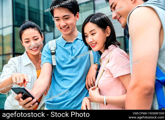 Outdoor four college students watch mobile phone