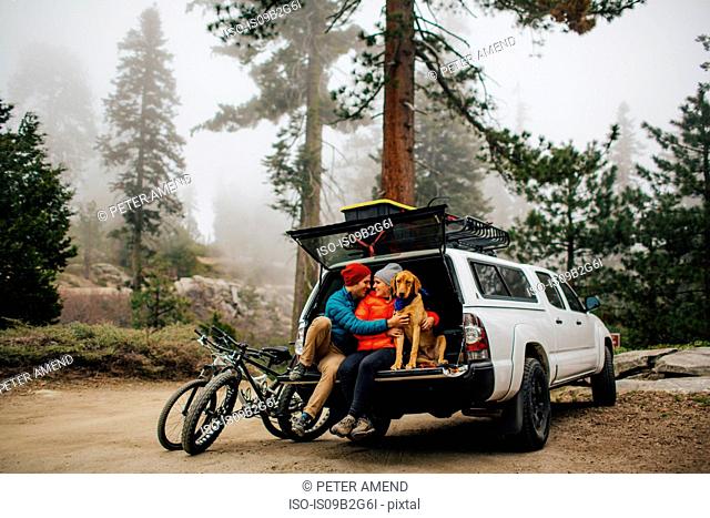 Couple and dog sitting on tailgate of jeep wagon, Sequoia National Park, California, USA