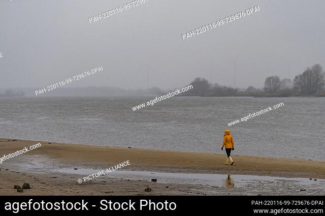 16 January 2022, Lower Saxony, Stove: A woman walks on the beach of the Elbe river in drizzle. Photo: Philipp Schulze/dpa