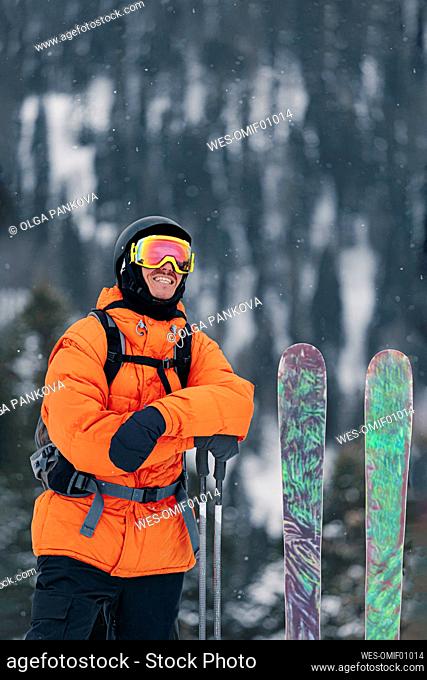 Smiling man in warm clothing with skis and poles