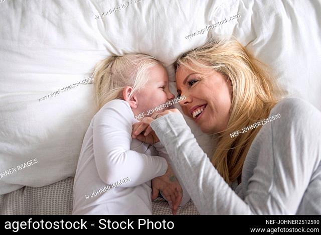 Mother and daughter cuddling in bed