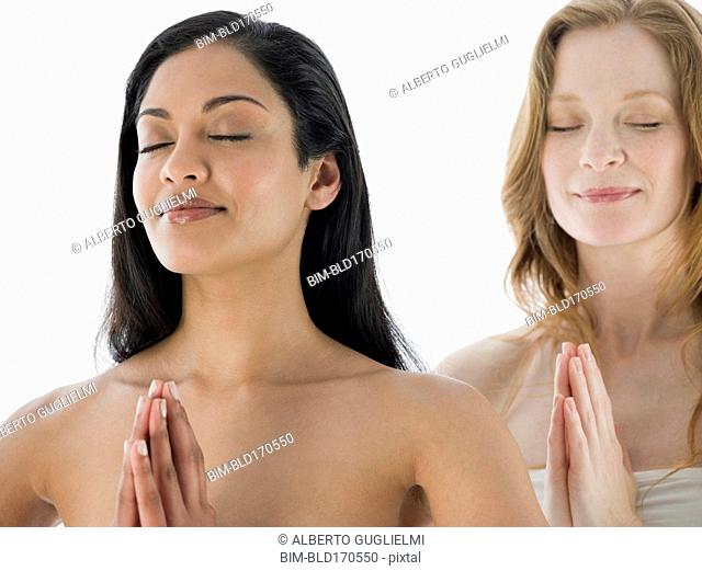 Smiling women meditating with hands clasped