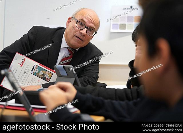 04 December 2023, Hamburg: Ties Rabe (SPD), Senator for Schools and Vocational Training in Hamburg, talks to pupils during digital German lessons in class 7h at...