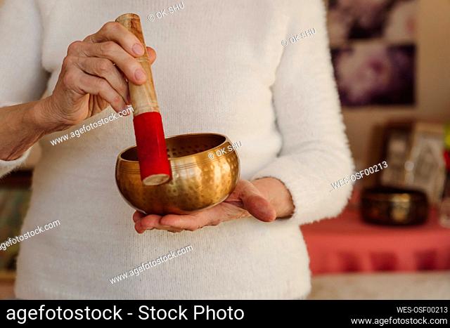 Hands of retired senior woman holding singing bowl